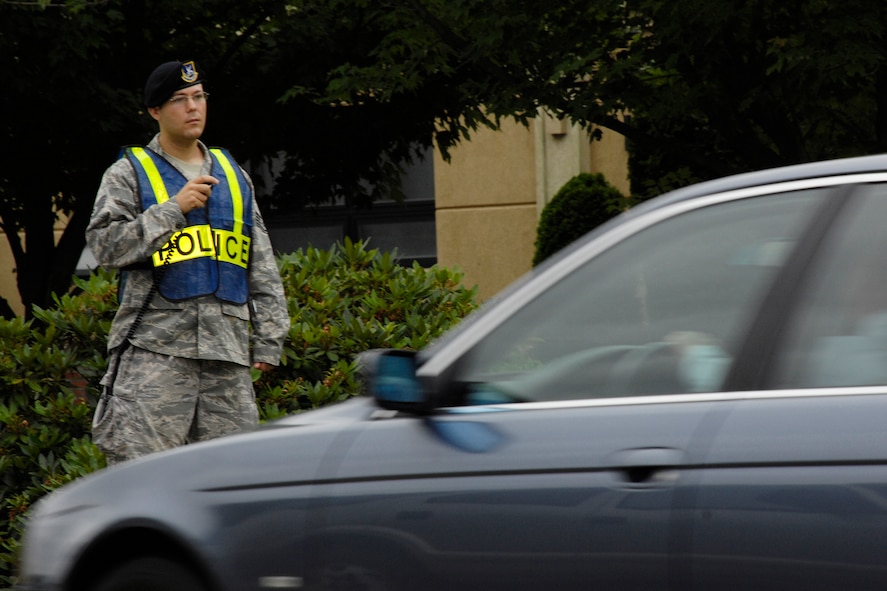 HANSCOM AIR FORCE BASE, Mass. - Staff Sgt. Michael Mandello, the 66th Security Forces Squadron noncommissioned officer in charge of police services observes eastbound traffic on Barksdale Street for traffic violations Aug. 13. Sergeant Mandello radios other members 66 SFS to wave violators into a parking lot further down the road to be issued a traffic fine. Most infractions were for using a cellular phone while driving or not wearing a seatbelt. (U.S. Air Force photo by Linda LaBonte Britt)