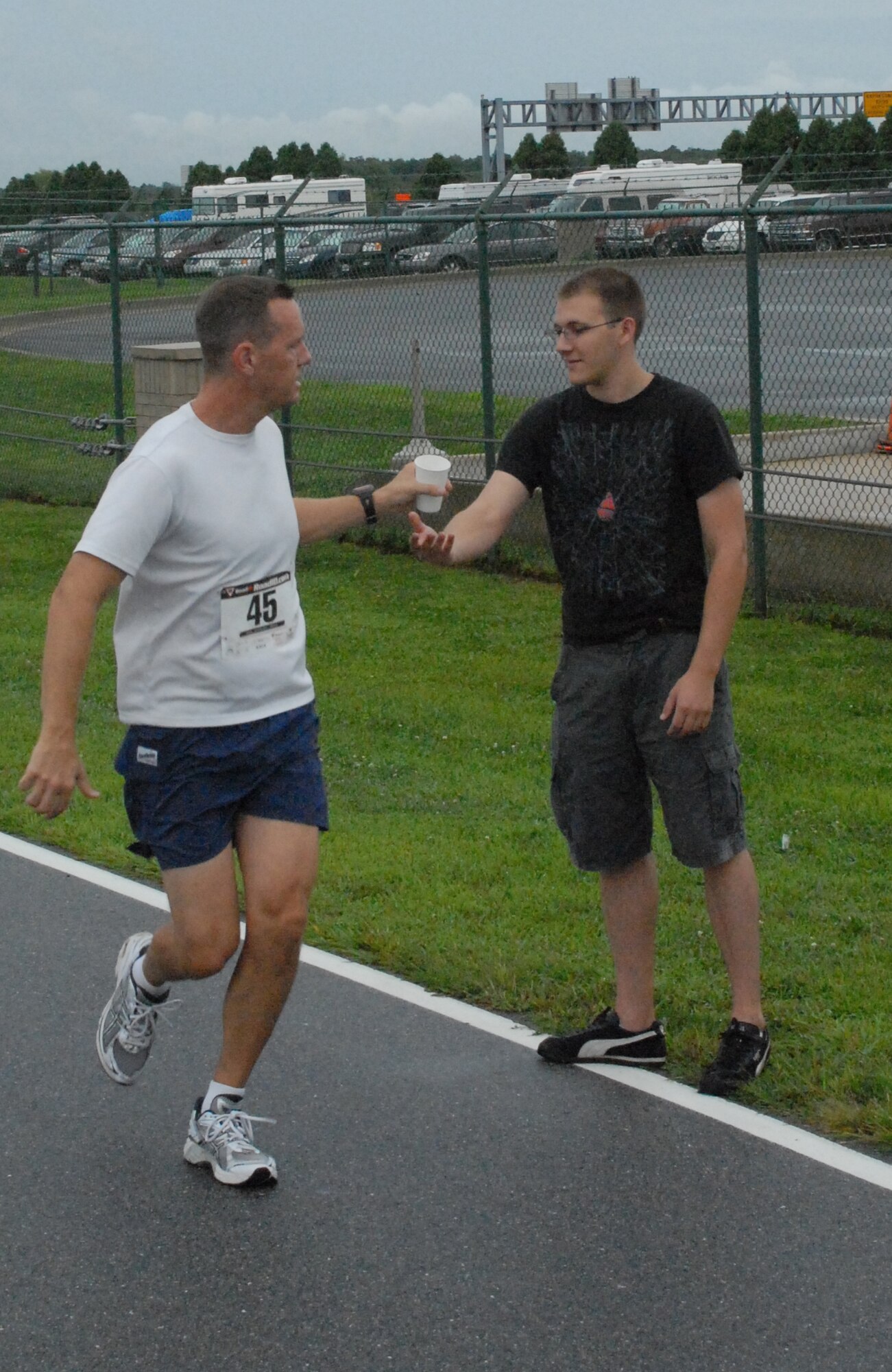 Matthew Holm takes a cup of water from Zachary Zilm during the ?Summer Sizzler,? Dover?s first 10-mile run Aug. 29.  A 10-mile run and a 5k fun run was held to prepare Air Force marathon participants for that event.  (U.S. Air Force photo/Staff Sgt. Chad Padgett)