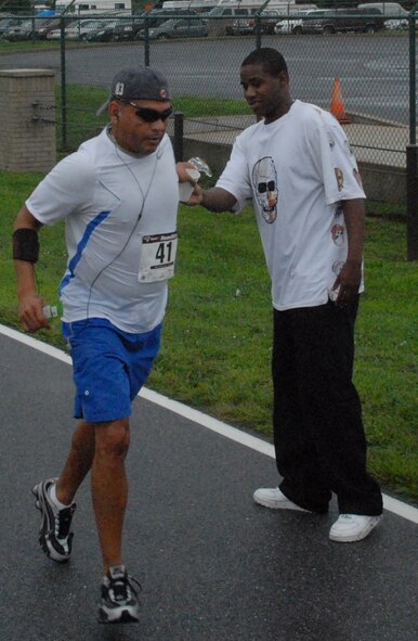 Francisco Ulloa grabs a cup of water from Trae Dashiell during the ?Summer Sizzler,? Dover?s first 10-mile run Aug. 29.  A 10-mile run and a 5k fun run was held to prepare Air Force marathon participants for that event.    (U.S. Air Force photo/Staff Sgt. Chad Padgett)
