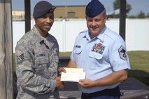MINOT AIR FORCE BASE, N.D. -- Senior Master Sgt. Michael Garrett, 5th Logistics Readiness Squadron fuels manager, receives a fundraiser check of 400 dollars from Tech. Sgt. Robert Furbush, 5th Security Forces Squadron military working dogs noncommissioned officer-in-charge, to help in the costs of treating his wife for lung cancer Aug. 31 here. A non-profit charity organization comprised of Warbirds and Rough Riders pulled together to support an Airman in need by organizing a fundraiser. (U.S. Air Force photo by Airman 1st Class Benjamin Stratton)
