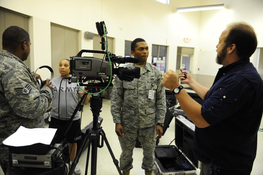 Erich Schwab (right), holiday greetings coordinator, goes over slating information with Air Force broadcaster Tech. Sgt. Dwight Hawkins, while Air Force Staff Sgt. James Zannetti gets shooting tips from Army broadcaster Staff Sgt. Kim Williams during early packing and preparations for upcoming holiday greetings. Three teams will depart shortly after Labor Day and will set up at overseas locations through the latter part of October.  (U.S. Air Force photo/Senior Airman Christopher Griffin)