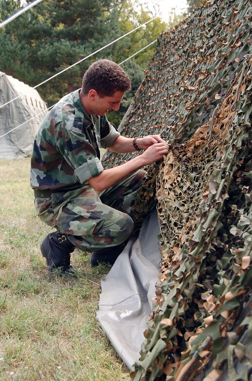 NIS, Serbia – A member of the Serbian Armed Forces places camouflage netting on a recently-erected tent in tent city Aug. 31 for the military medical training exercise in Central and Eastern Europe, better known as MEDCEUR 2009, in Nis, Serbia. The medical exercise, running Sept. 2-13, will host 15 nations from Central and Eastern Europe and the U.S. (U.S. Air Force photo/Senior Airman Kali L. Gradishar)