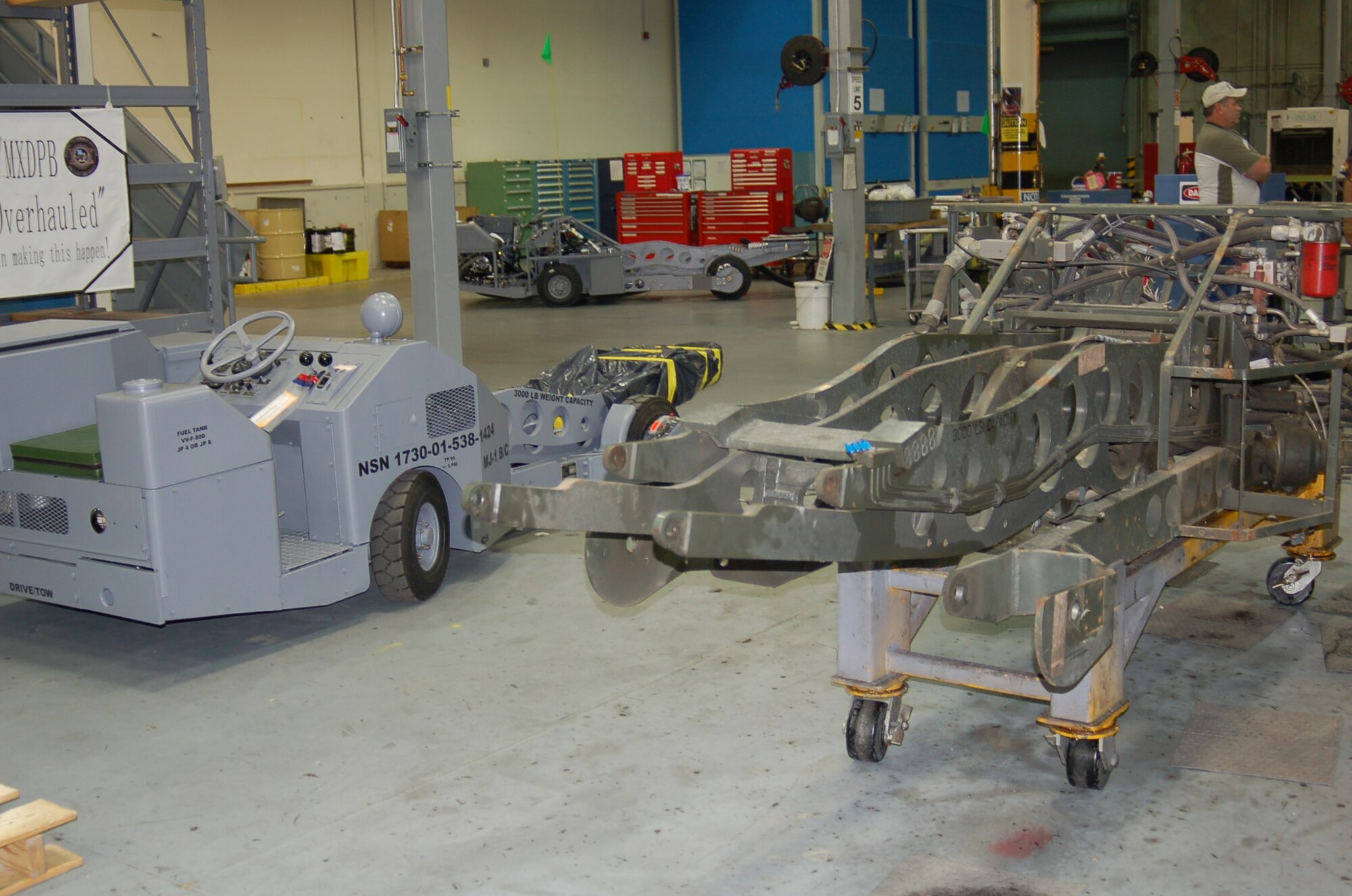 A completed MJ-1 Bomb Lifter, left, is shown next to one beginning the overhaul process. The unfinished lifter sits on a rolling stand, designed by 526 EMXS mechanics, to make it easier to move the truck through the overhaul cells.