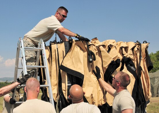 U.S. Air Force Master Sgt. Ryan Leith (top), 435th Expeditionary Air Ground Operations Group medical technician, along with fellow contingency response group members, set up a tent in the Knez Mihailo Barracks in Nis, Serbia, Aug. 29, 2009. Sergeant Leith, along with 31 fellow 435th Air Ground Operations Wing members, deployed to Serbia for two weeks in support of the Medical Training Exercise in Central and Eastern Europe 2009, better known as MEDCEUR 2009.(U.S. Air Force photo by Staff Sgt. Markus M. Maier)
