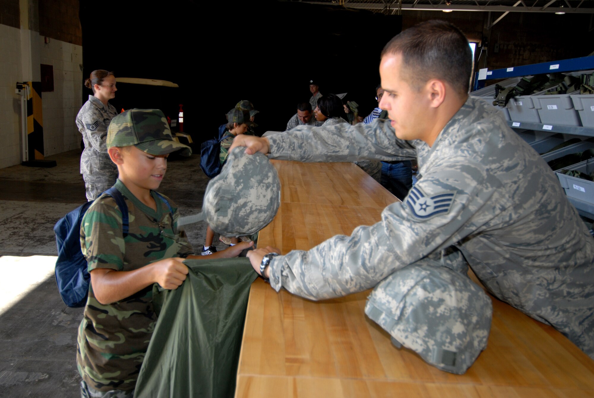 HICKAM AIR FORCE BASE, HAWAII -- Sam Barrett, 10, son of Colonel Sam Barrett, 15th Airlift Wing vice commander, recieves a helmet from Staff Sgt. Jason Huthings to complete his mobility bag while he goes through the mobility processing line during the sixth annual Operation Hele On, Aug. 21. Hele On is a program meant to give children of military members an idea of what goes on during a deployment. During the event, kids learned how to march, were issued mobility bags, and were bussed out to the Hickam flight line to tour a C-17 Globemaster III to simulate a deployment. (U.S. Air Force photo/Senior Airman Gustavo Gonzalez)