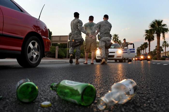 Tech Sgt. Costello Williams, Senior Airman Pat Hinkel and Airman 1st Class Nikolas Nicely from the 99th Security Force Squadron simulate detaining Airman 1st Class Brett Clashman for a possible DUI.  The simulation was done to show the consequences of Driving under the Influence of Alcohol.(U.S. Air Force photo illustration by Tech. Sgt Michael R. Holzworth)