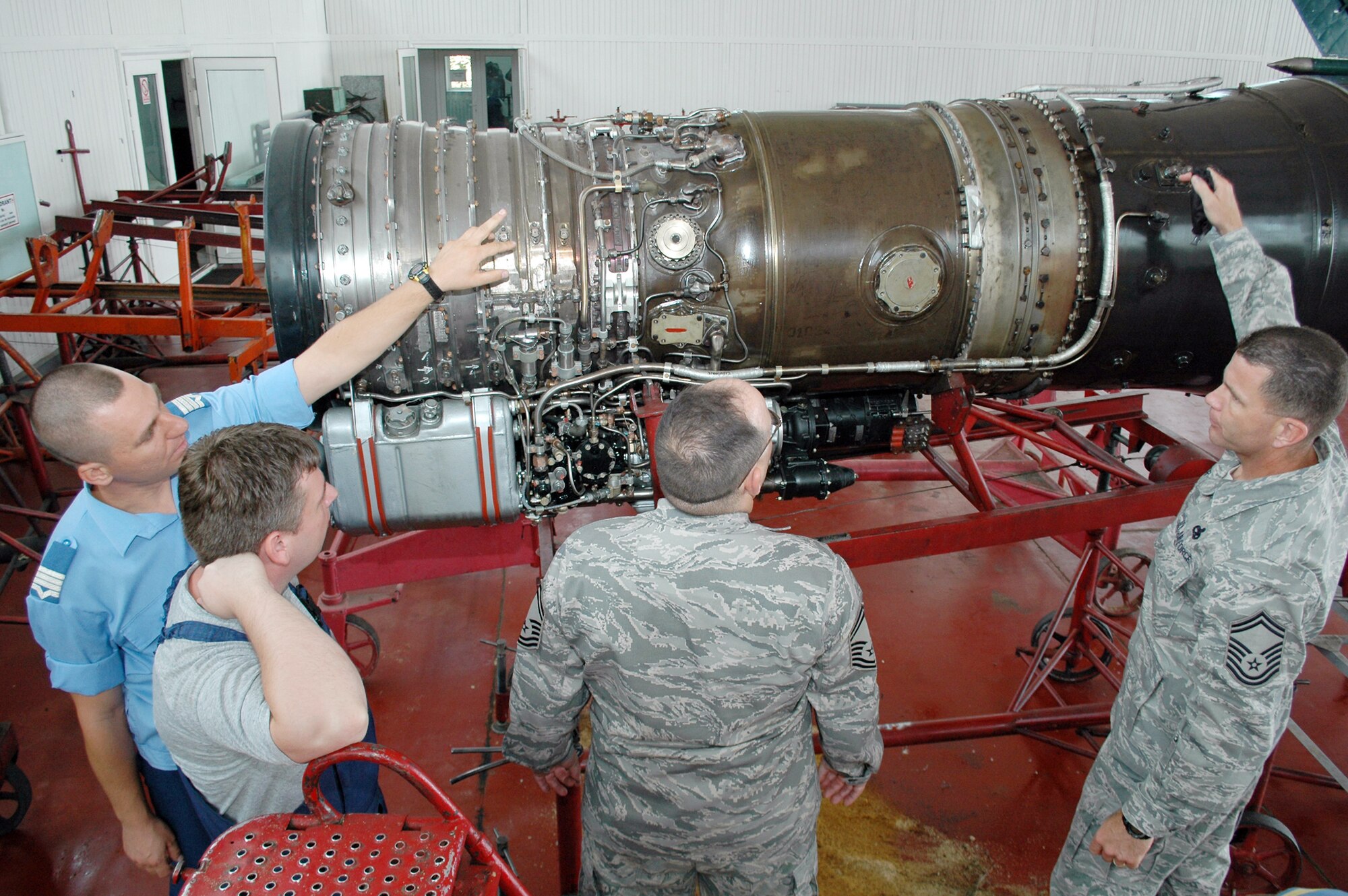 Romanian air force Warrant Officer Second Class Dima Valentin, (far left) discusses the inner workings of the MiG-21 Lancer fighter engine with two senior NCOs from the 31st Maintenance Group Aug. 26, 2009 at the 86th Air Base in Fetesti, Romania. The two NCOs were part of a three-person U.S. Air Forces in Europe maintenance NCO training program traveling contact team who met with Romanian air force aircraft maintainers and warrant officer and NCO school instructors Aug. 25 through 28. (U.S. Air Force photo/Tech. Sgt. Michael O'Connor) 