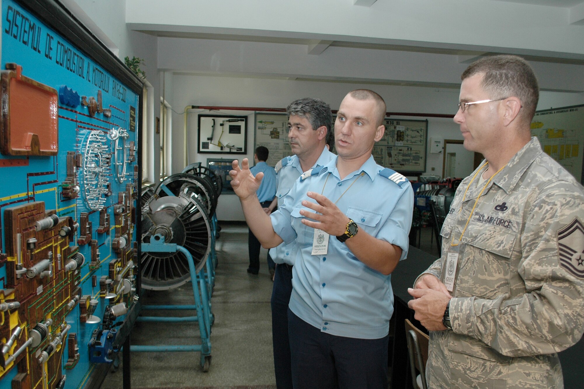Romanian air force Warrant Officer Second Class Dima Valentin (middle) discusses an aircraft maintenance diagram with Senior Master Sgt. Timothy Kellner Aug. 25, 2009 in Boboc, Romania. Sergeant Kellner's visit to the Traian Vuia Air Force Warrant Officer and NCO Military School is part of a three-person U.S. Air Forces in Europe maintenance NCO training program traveling contact team who met with Romanian air force aircraft maintainers and warrant officer and NCO school instructors Aug. 25 through 28. Romanian Warrant Officer Valentin is a MiG-21 Lancer electrician. Sergeant Kellner is the 31st Maintenance Group quality assurance superintendent. (U.S. Air Force photo/Tech. Sgt. Michael O'Connor)