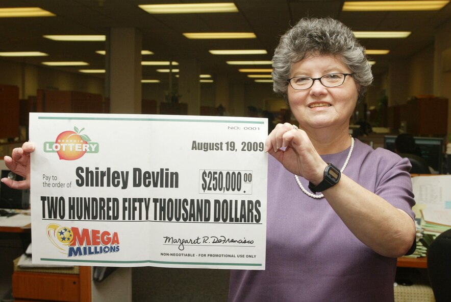 Shirley Devlin, the military pay supervisor for the 94th Finance Office, holds up her  check for $250,000 Sept. 2. Ms. Devlin correctly matched the first five numbers during a multiple-state lottery drawing last month. She plans on buying a new car when she retires soon. (U.S. Air Force photo/Don Peek)