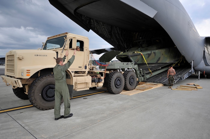 Senior Airman Scott Skinner marshals a U.S. Navy Riverine Command Boat and trailer onto a C-17 at Charleston AFB Aug. 26. The U.S. Navy's Riverine Group 1 is testing the RCB, which gives riverine squadron's the ability to travel in rivers, bays and coastal regions, expanding the capabilities of command and control and the riverine squadron's maritime security reach. Airman Skinner is a loadmaster with the 15th Airlift Squadron. (U.S. Air Force photo/James M. Bowman(