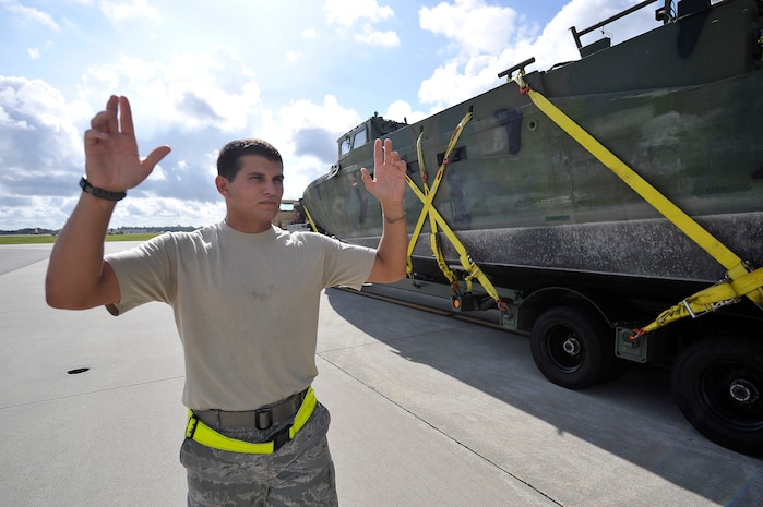 Senior Airman Richard Babb marshals a U.S. Navy Riverine Command Boat and trailer onto a C-17 at Charleston AFB Aug. 26. The U.S. Navy's Riverine Group 1 is testing the RCB, which gives riverine squadron's the ability to travel in rivers, bays and coastal regions, expanding the capabilities of command and control and the riverine squadron's maritime security reach. Airman Babb is an air transportation journeyman with the 437th Aerial Port Squadron. (U.S. Air Force photo/James M. Bowman(