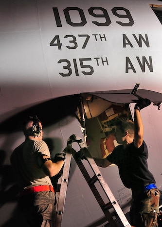 Senior Airman Marcus Williams, right, and Senior Airman Fred Hess store mounting points used to liftthe nose of a C-17 during an operational checkout of the aircraft's landing gear here Aug. 27. The mounting points connected with aircraft jacks which held up the nose when the landing gear was raised. Airman Williams is a hydraulic systems journeyman with the 437th Aircraft Maintenance Squadro and Airman Hess is a jet propulsion technician with the 437 AMXS. (U.S. Air Force photo/Staff Sgt. Daniel Bowles)