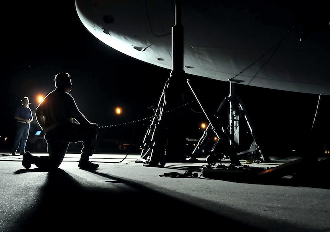 Master Sgt. Richard Keadle kneels at the nose of a C-17 while supervising the progress of an operational checkout of a C-17's landing gear on the flightline here Aug. 27. Sergeant Keadle communicated with technicians seated in the cockpit during the check and visually verified each time the gear was raised and lowered. Sergeant Keadle is a maintenance supervisor with the 315th Aircraft Maintenance Squadron. (U.S. Air Force photo/Staff Sgt. Daniel Bowles)