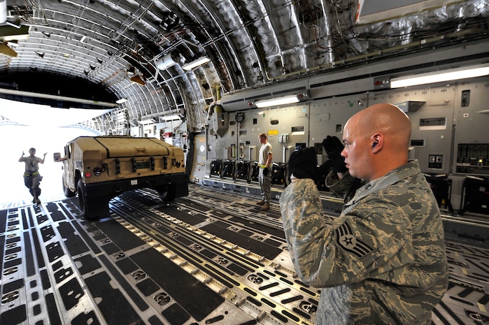 Staff Sgt. Nathan Dunn marshals a High Mobility Multipurpose Wheeled Vehicle into a C-17 at Charleston AFB Aug. 24. The loading of the HMMVV marked Sergeant Dunn's 500th cargo load. Sergeant Dunn is an aerial port expeditor with the 437th Aerial Port Squadron. (U.S. Air Force photo by James M. Bowman/released)