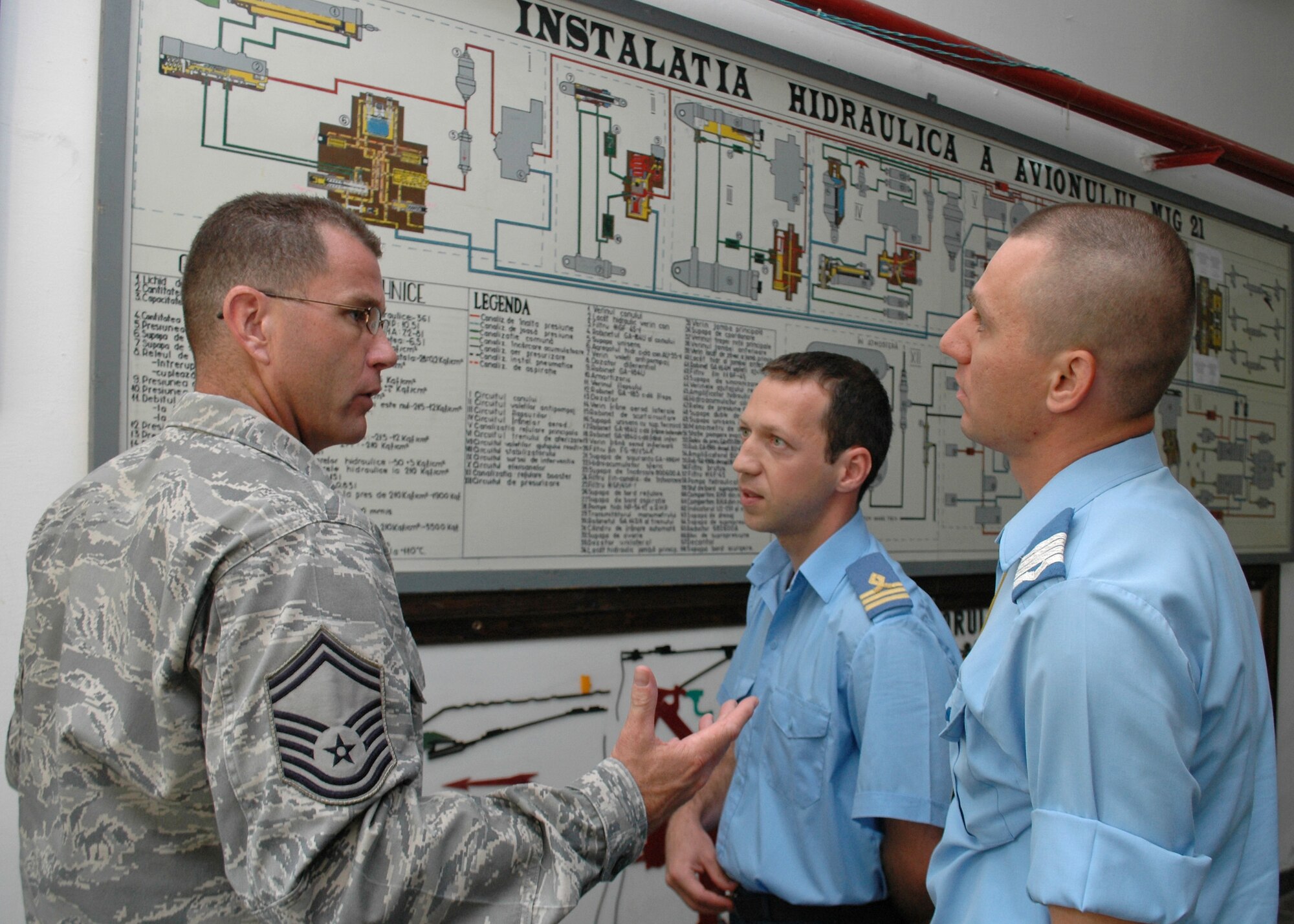 Senior Master Sgt. Timothy Kellner, 31st Maintenance Group quality assurance superintendent, asks Romanian Air Force Warrant Officer Second Class Dima Valentin, (far right), questions about the hydraulic system for the MiG-21 Lancer Aug. 25, 2009.  Sergeant Kellner’s visit to the Traian Vuia Air Force Warrant Officer and NCO Military School in Boboc, Romania, is part of a three-person U.S. Air Forces in Europe Maintenance NCO Training Program Traveling Contact Team who met with RoAF aircraft maintainers and WO and NCO school instructors Aug. 25-28.  (U.S. Air Force photo/Tech. Sgt. Michael O’Connor)