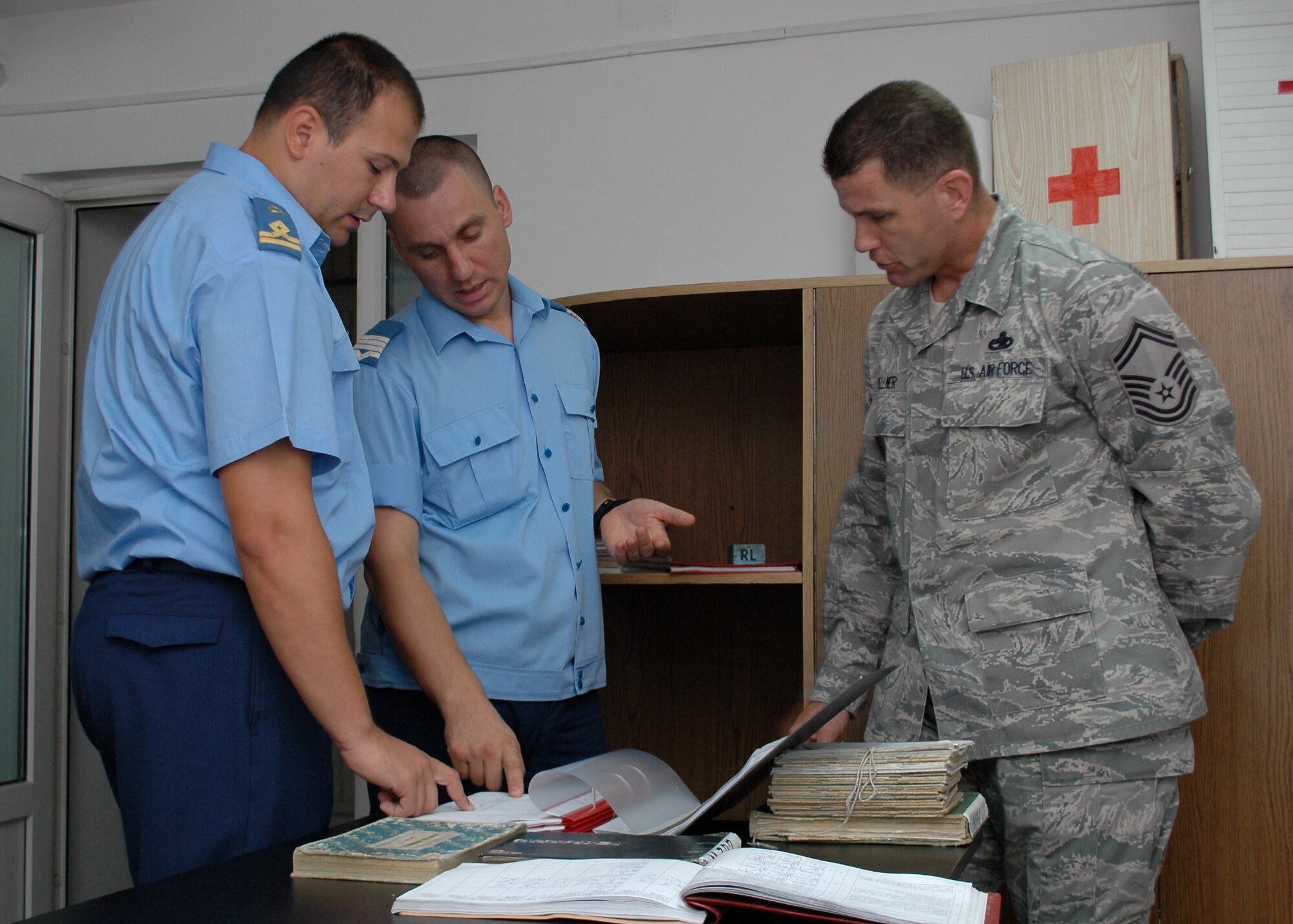 Romanian Air Force 1st Lt. Gabriel Tanase, (far left), and Warrant Officer Second Class Dima Valentin from the 86th Air Base in Fetesti, Romania, discuss how maintenance on the MiG-21 Lancer is documented in their log books Aug. 26, 2009, with Senior Master Sgt. Timothy Kellner, 31st Maintenance Group quality assurance superintendent.  Sergeant Kellner was part of a three-person U.S. Air Forces in Europe Maintenance NCO Training Program Traveling Contact Team who met with RoAF aircraft maintainers and WO and NCO school instructors Aug. 25-28.  (U.S. Air Force photo/Tech. Sgt. Michael O’Connor)