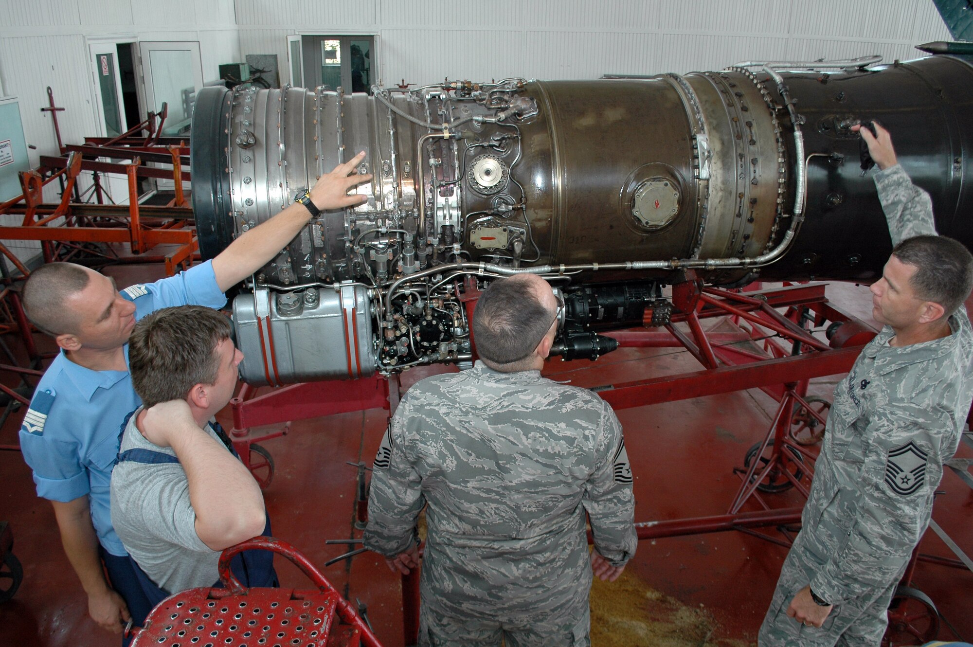 Romanian Air Force Warrant Officer Second Class Dima Valentin, (far left), from the 86th Air Base in Fetesti, Romania discuss the inner workings of the MiG-21 Lancer fighter engine Aug. 26, 2009, with two senior NCOs from the 31st Maintenance Group.  The two NCOs were part of a three-person U.S. Air Forces in Europe Maintenance NCO Training Program Traveling Contact Team who met with RoAF aircraft maintainers and WO and NCO school instructors Aug. 25-28.  (U.S. Air Force photo/Tech. Sgt. Michael O’Connor)
