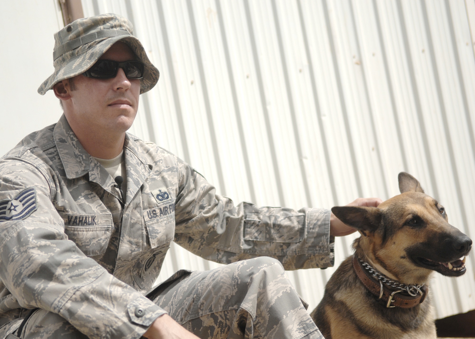 Tech. Sgt. Jerome Vahalik IV pets Max, a military working dog, Aug. 28, 2009, at Joint Base Balad, Iraq. Max, a German shepherd, is trained to perform patrol and detection. Sergeant Vahalik is the 732nd Expeditionary Security Forces Squadron kennel master. (U.S. Air Force photo/Senior Airman Christopher Hubenthal) 
