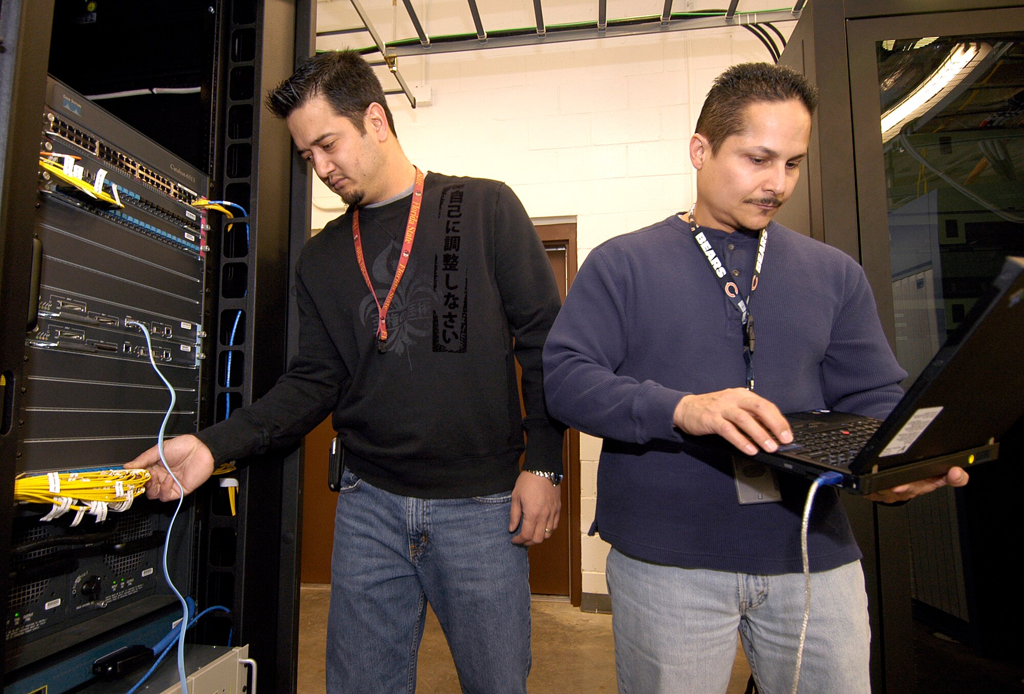 Communications professionals Rob Ludwig, left, and Rick Cruz of the 72nd Communications Squadron, work in an information transfer node, an area where thousands of Tinker network and phone customers connect to the network. Functions of the 72nd Communications Squadron will soon move under the Information Technology Directorate. (Air Force photo by Margo Wright) 