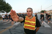 Air Force Basic Military Training trainee Oscar Carrillo, 320th Training Squadron, performs road guard duties on Lackland while flight 457 crosses the road and heads to the drill pad for parade practice. (U.S. Air Force photo/Robbin Cresswell)