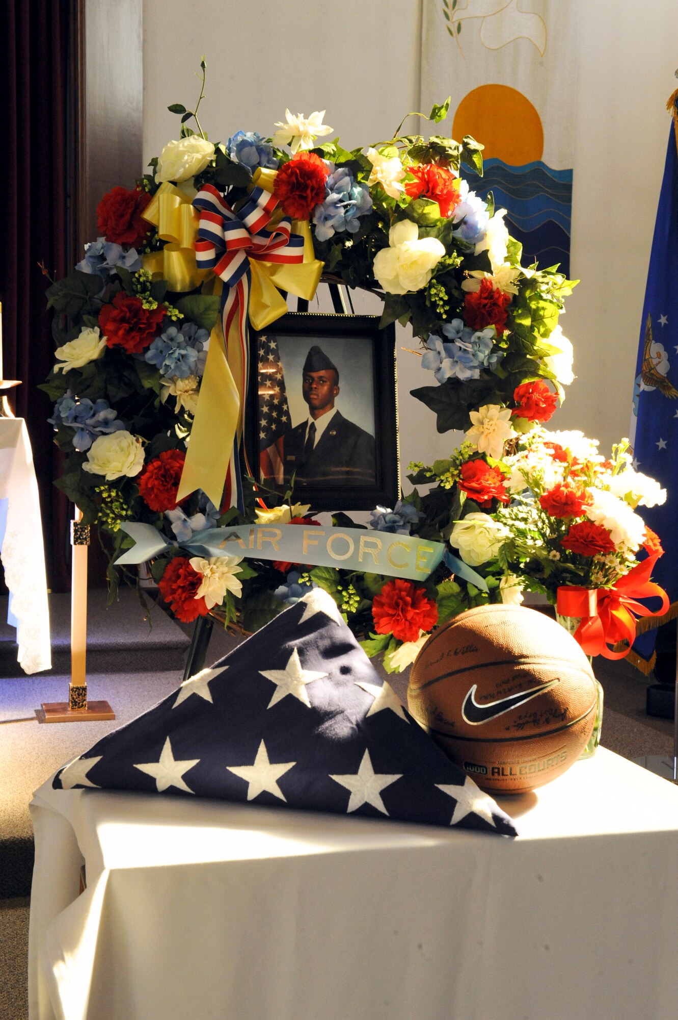 ELMENDORF AIR FORCE BASE, Alaska -- The memorial wreath for Airman 1st Class Fleming, 3rd Civil Engineer Squadron, which consisted of flowers, an Air Force sash, a folded flag and a basketball signed by his flight members stands at the front of his memorial ceremony Aug. 27. The ceremony, which honored Fleming, consisted of friends sharing stories, prayer and song. (U.S. Air Force photo/Staff Sgt. Joshua Garcia)