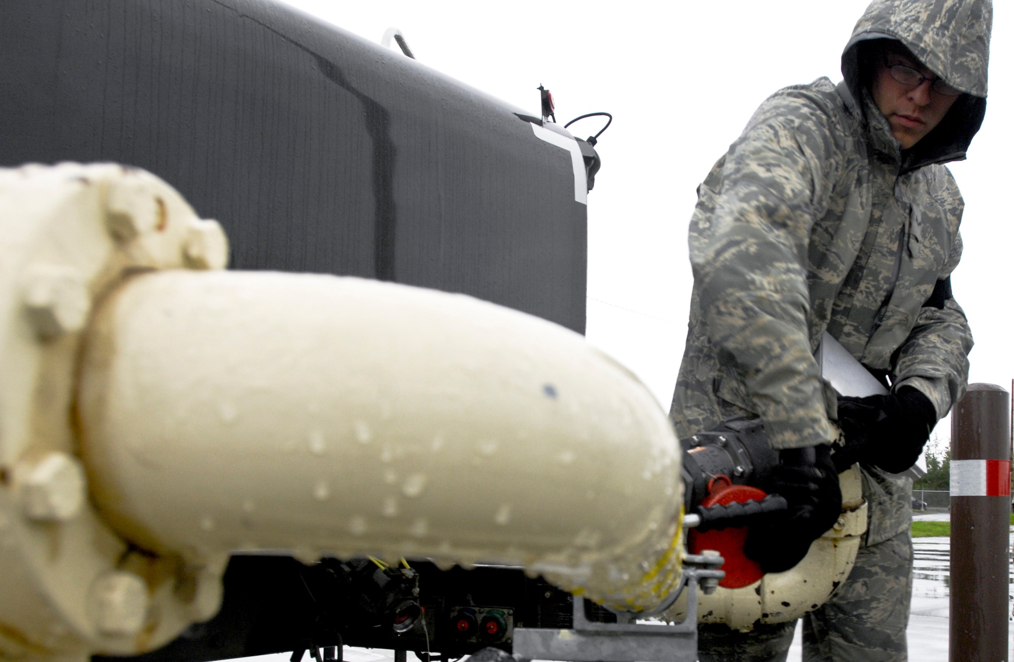 ELMENDORF AIR FORCE BASE, Alaska -- Airman 1st Class Nathan Lewis, 3rd Logistics Readiness Squadron, folds in the Plus 100 hose. Elmendorf began the using  Plus 100 additive in their JP-8 aviation fuel Sept. 1. The additive helps prevent buildup in F-15 Eagle and F-22 Raptor engines; therefore it will reduce the amount of maintenance needed on those engines.  (U.S. Air Force photo/Airman 1st Class Christopher Gross)