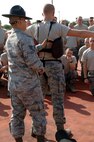 Staff Sgt. Matthew Pilch, a military training instructor from Lackland's 737th Training Support Squadron, demonstrates how to properly put on protective gear before the pugil stick fighting matches. The pugil stick fighting portion of Air Force Basic Military Training is held during the 5th week of training and helps teach basic self defense techniques. (U.S. Air Force photo/Senior Airman Nicole Roberts) 