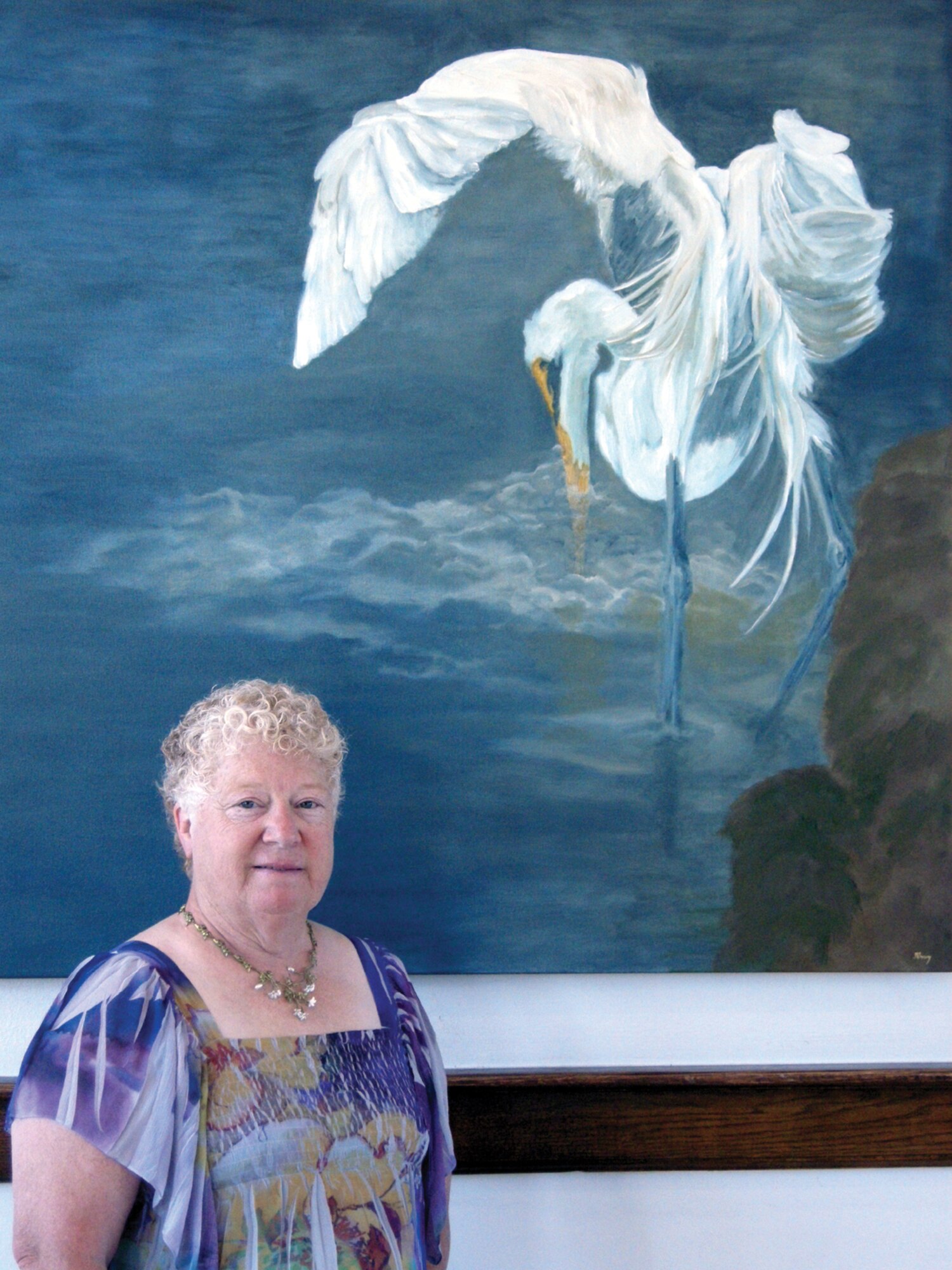 Artist Janet Sherry poses with one of her portraits, titled “Gone Fishin’.” The heron is fishing for food and the half submerged beak makes the statement, “did the he catch the fish or not?” (Air Force photos by Becky Pillifant)