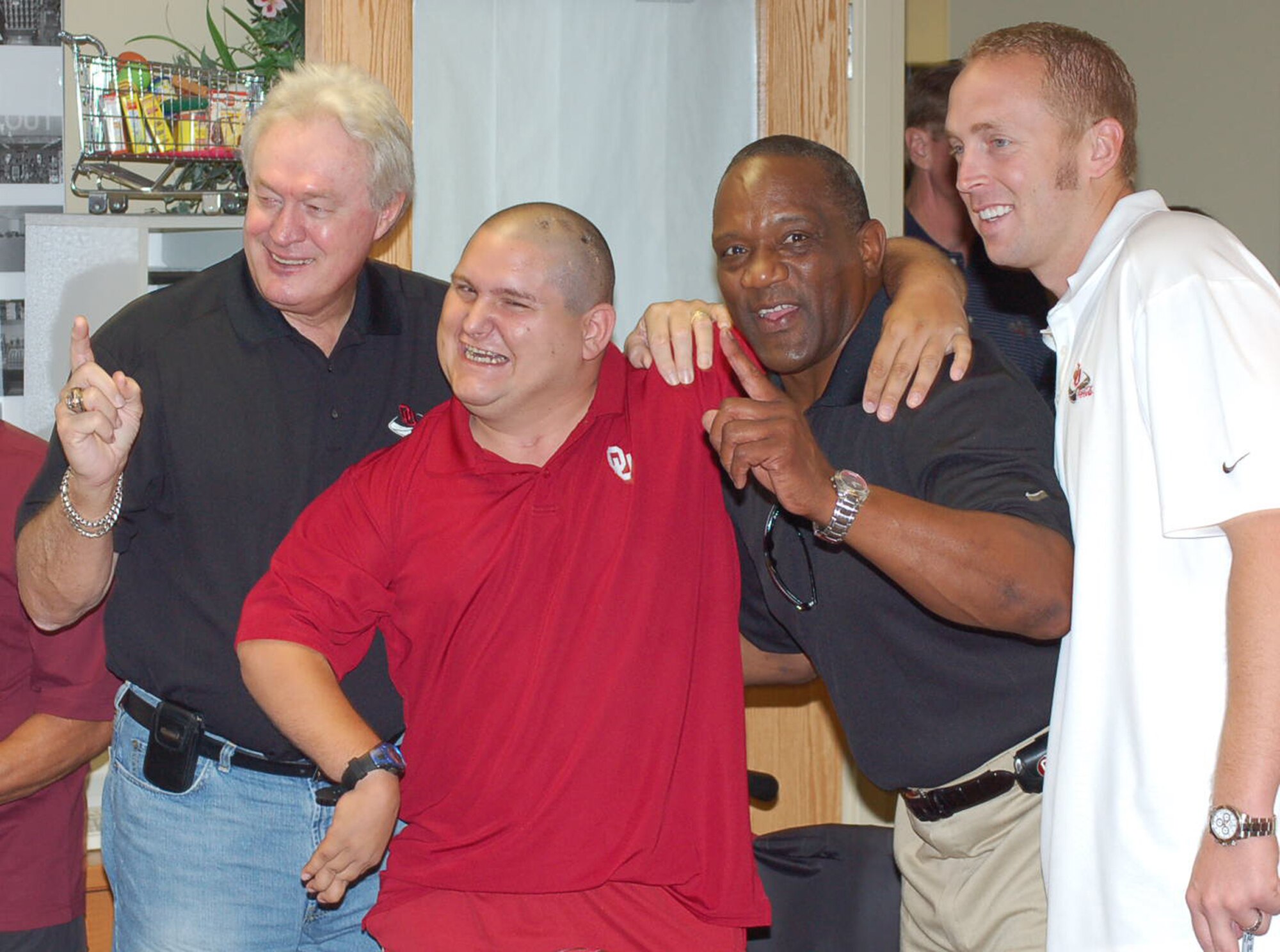 Tinker Commisary patron Travis Thomas is all smiles as his picture is taken with University of Oklahoma Heisman Trophy winners, from left, Steve Owens, Billy Simms and Jason White. The trophy-winning trio met with fans and signed autographs at the Tinker Commissary on Aug. 29. (Air Force photo by John E. Banks )
