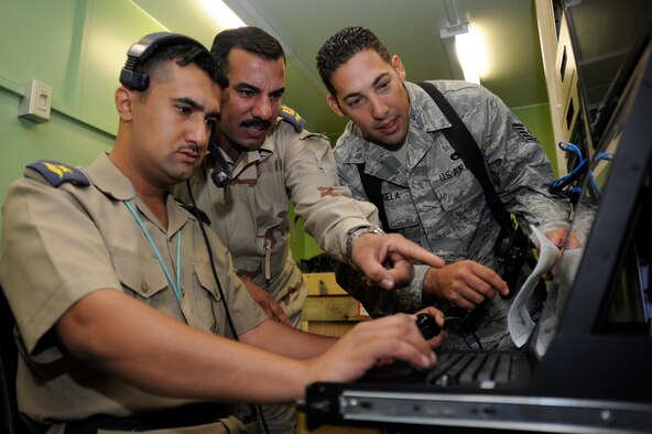 FORWARD OPERATING BASE DELTA, Iraq -- Air Force Tech. Sgt. Paul Valenzuela, advisor assigned to the Iraq Training and Advisory Mission - Air Force, coaches Iraqi air force officers during an intelligence, surveillance, and reconnaissance training mission here Aug. 30, 2009. The Iraqi officers direct ISR aircraft and control camera movement from this fixed ground station to provide full-motion ISR video for operations in Iraq.  Sergeant Valenzuela is deployed from Travis Air Force Base, Calif., and is a native of Wichita Falls, Texas.  (U.S. Air Force photo/Tech. Sgt. Johnny L. Saldivar)   