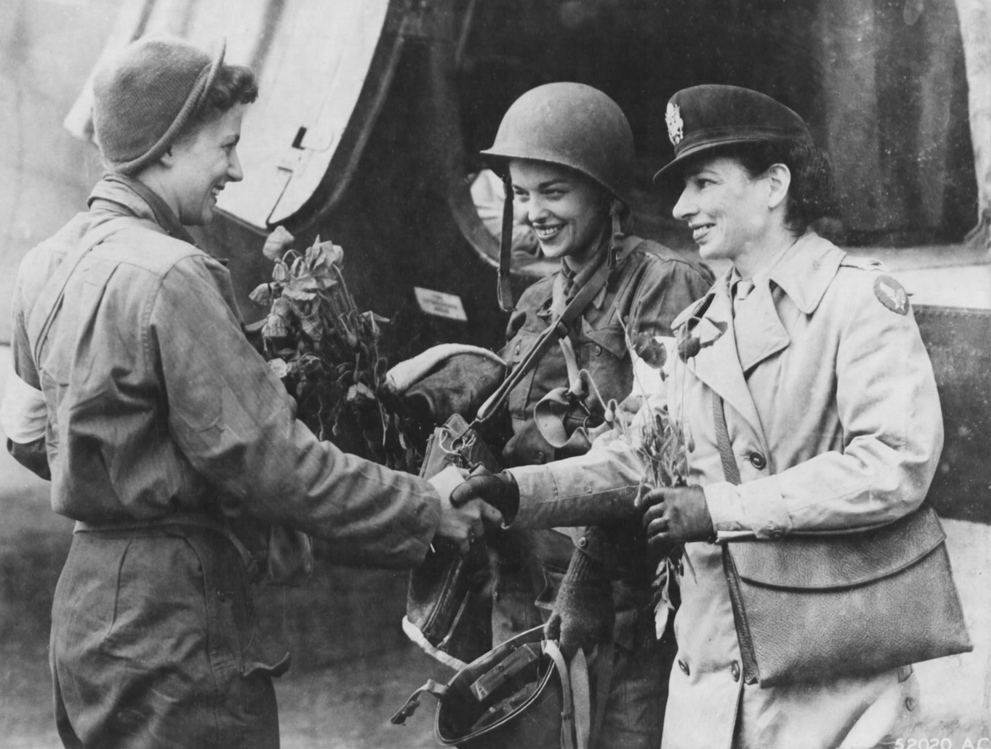Two of the first flight nurses to make evacuation flights into Normandy after D-Day, Lts. Suella Bernard (left) and Marijean Brown (center) are greeted by Lt. Foster, their head nurse. They are holding poppies they brought back from the Normandy beachhead. (U.S. Air Force photo)