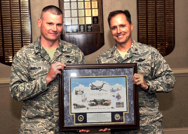 Col. John Wood presents Capt. Rick Muller with a lithograph to culminate his tenure at Charleston AFB as he and his wife Capt. Heather Mueller move to their next assignment in Washington D.C. Colonel Wood is the 437th Airlift Wing commander and Captain Muller is a 437th Airlift Wing executive officer. (U.S. Air Force photo/James Bowman)  