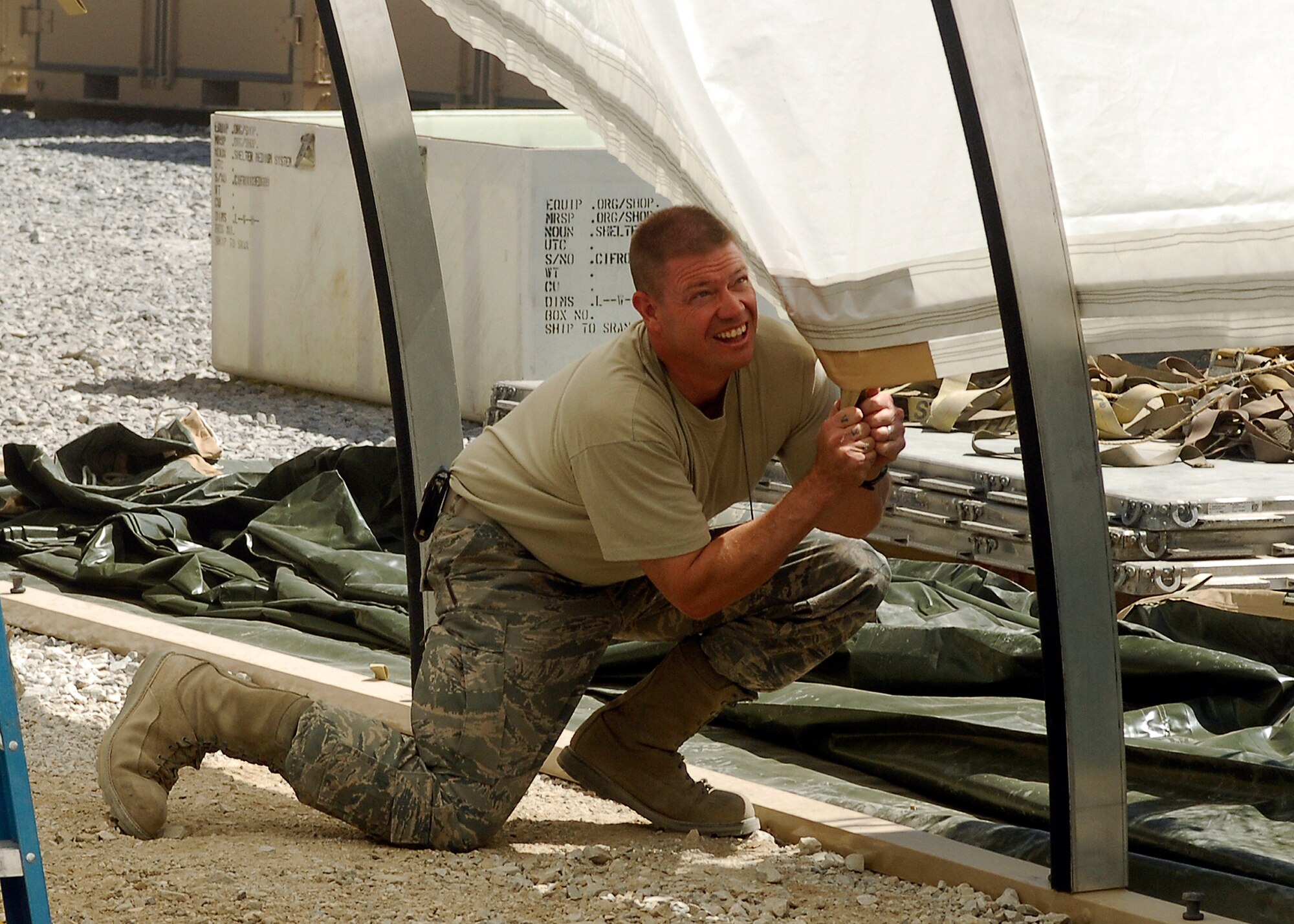 BAGRAM AIRFIELD, Afghanistan -- Staff Sgt. Troy Jorgenson, an Engineering Assistant from 455th Expeditionary Civil Engineering Squadron, pulls down the side of the fire guard in order to secure it to the California Tent structure here, Sept. 3, 2009.  Sergeant Jorgenson is deployed from the Nevada Air National Guard and hails from Reno, Nev.  The ECES is responsible for manpower resources, billeting and local national force protection escorts operations.  (U.S. Air Force photo/Senior Airman Felicia Juenke)