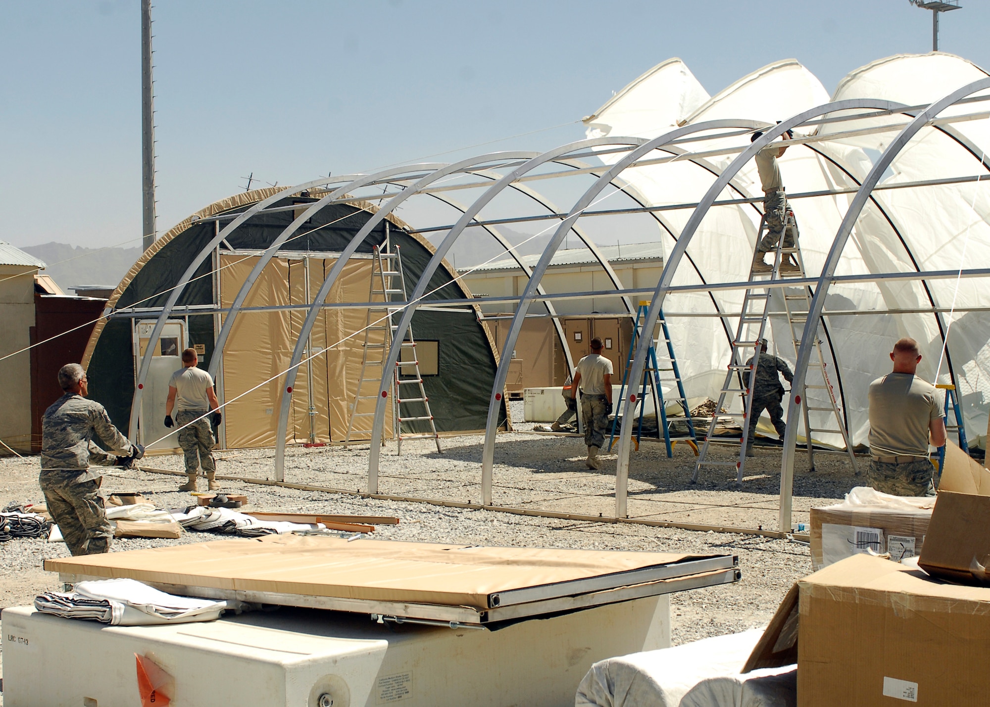 BAGRAM AIRFIELD, Afghanistan -- Members from the 455th Expeditionary Civil Engineering Squadron work together to put up a California Tent here, Sept 3, 2009.  The ECES put together tents only with special permission.  This particular tent is being placed behind the supply yard for extra storage.  The ECES is responsible for manpower resources, billeting and local national force protection escort operations.  (U.S. Air Force photo/Senior Airman Felicia Juenke)
