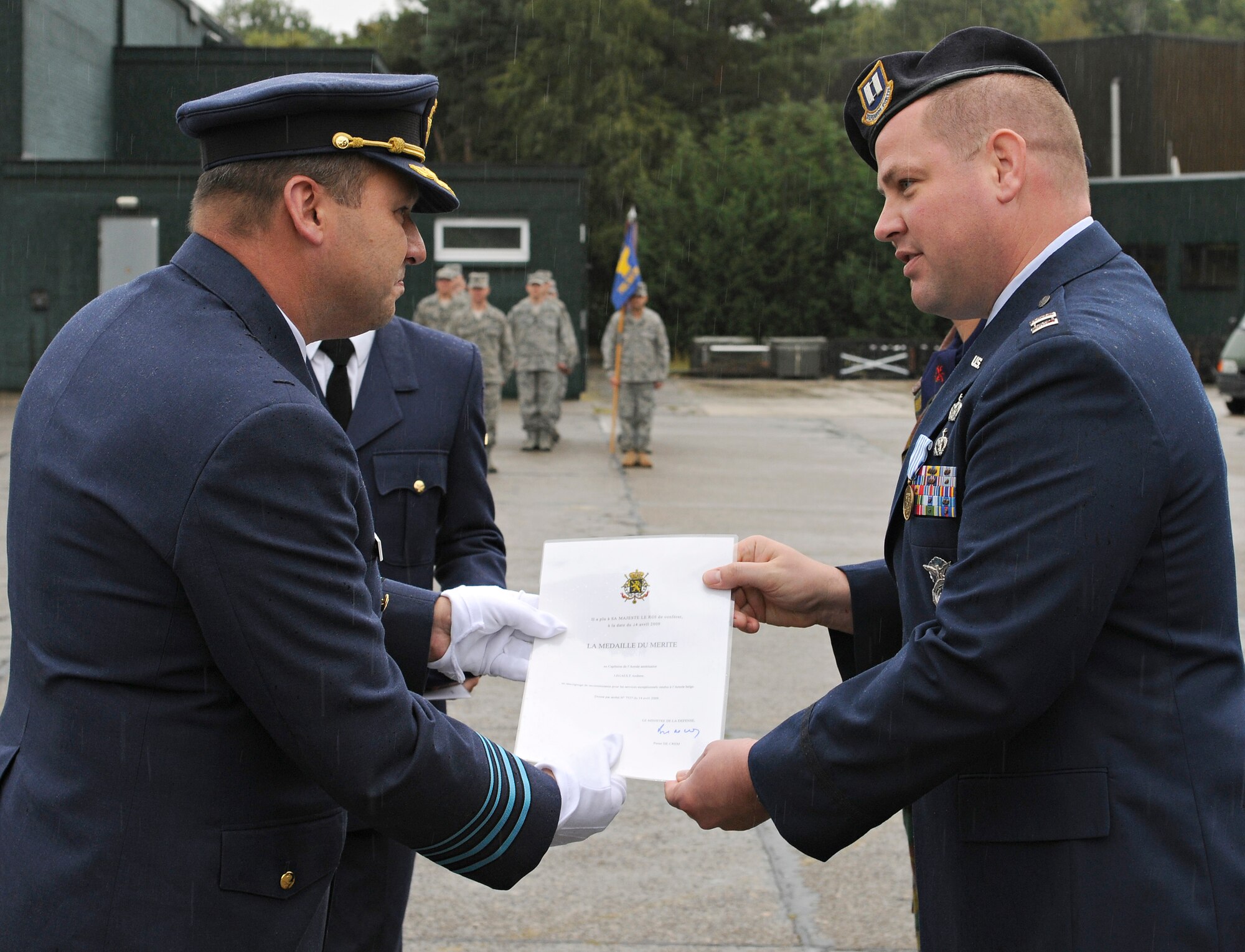 SPANGDAHLEM AIR BASE, Germany – Maj. Gen Claude Van De Voorde, Belgian air force 10th Tactical Wing commander, presents Capt. Andrew Legault, 701st Munitions Support Squadron security forces commander, with a certificate for the Belgian Meritorious Medal during the 10th TW change of command ceremony Sept. 1. Captain Legault received the medal for outstanding efforts resulting in excellent ratings during the most recent weapons inspection at Kleine Brogel Air Base, Belgium. (U.S. Air Force photo/Senior Airman Benjamin Wilson)