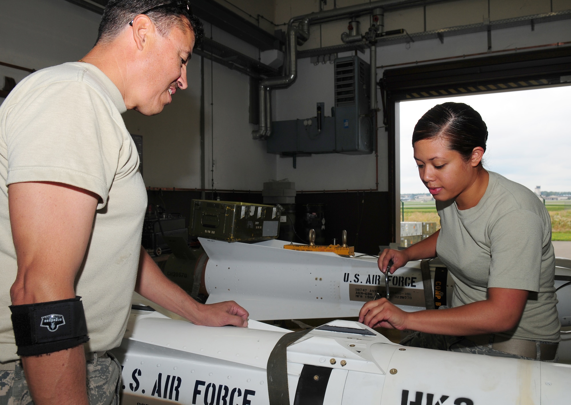 U.S. Air Force Master Sgt. Eugene Rinaldi (left), Air Force Reserve Ammunition Team member, and Airman 1st Class Ritchlyn Fryman, 86th Munitions Squadron precision guided munitions crew member, remove the guidance control section of an AGM-65 Maverick missile system for upgrades Aug. 11, 2009, Ramstein Air Base, Germany. More than 70 missiles were enhanced with a new software circuit card which allows for more accuracy and adds an abort code for pilots. (U.S. Air Force photo by Staff Sgt. Jocelyn Rich)