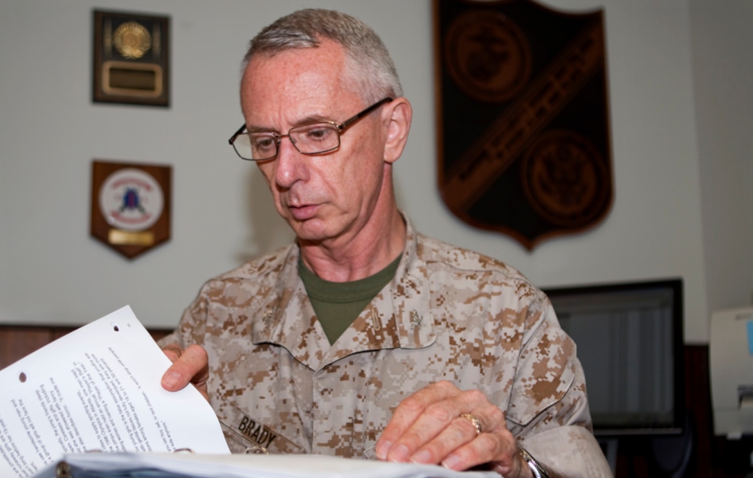 Col. Terry Brady, G-1 Assistant Chief of Staff, U.S. Marine Corps Forces, Pacific, sits at his desk while he looks through some of his memoirs before retiring Sept. 11. Brady was well known as an educator aboard Camp Smith, especially G-1, for conducting realistic and immersive learning environments instead of a more traditional slideshow.  (Official U.S. Marine Corps photo by Cpl. Achilles Tsantarliotis)(Released)