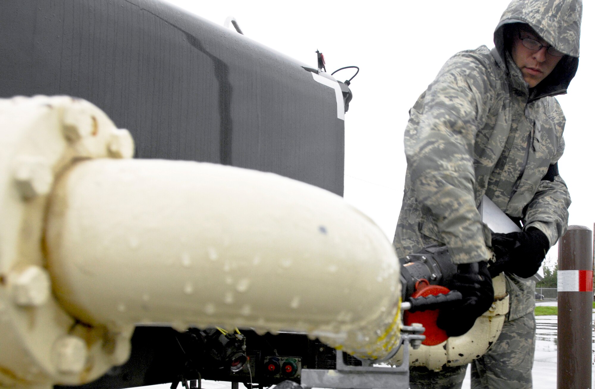 Airman 1st Class Nathan Lewis folds in the Plus 100 hose Sept. 1, 2009, at Elmendorf Air Force Base, Alaska. Base members began using Plus 100 additive in their JP-8 aviation fuel Sept. 1. The additive helps prevent buildup in F-15 Eagle and F-22 Raptor engines; therefore it will reduce the amount of maintenance needed on those engines. Airman Lews is assigned to the 3rd Logistics Readiness Squadron. (U.S. Air Force photo/Airman 1st Class Christopher Gross) 