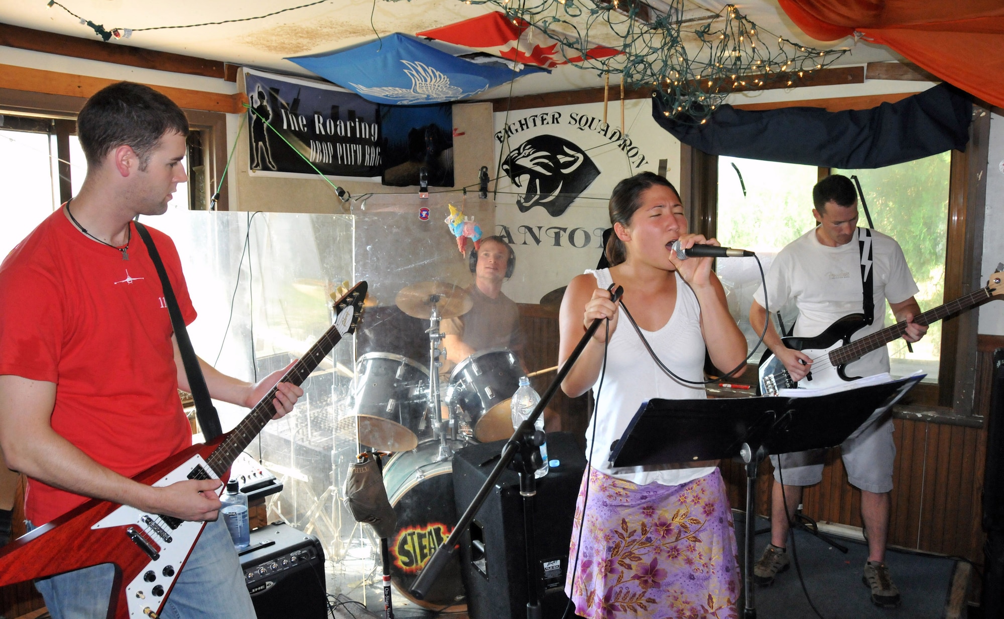 Capt. Alex "Tuna" Turner lays down the chords on the electric guitar; Capt. Kevin "Bama" Sweeney keeps the baseline beat on the drums; 1st Lt. Kristine "Sparkie" Knieff belts out a tune, and Lt. Col. Steve "Dallas" Horton blends with the bass during practice here Aug. 9. The captains are pilots with the 35th Fighter Squadron; the colonel is the 35th FS director of operations; and the lieutenant is an executive officer with the 8th Maintenance Group. They are members of Steal Wool.  
