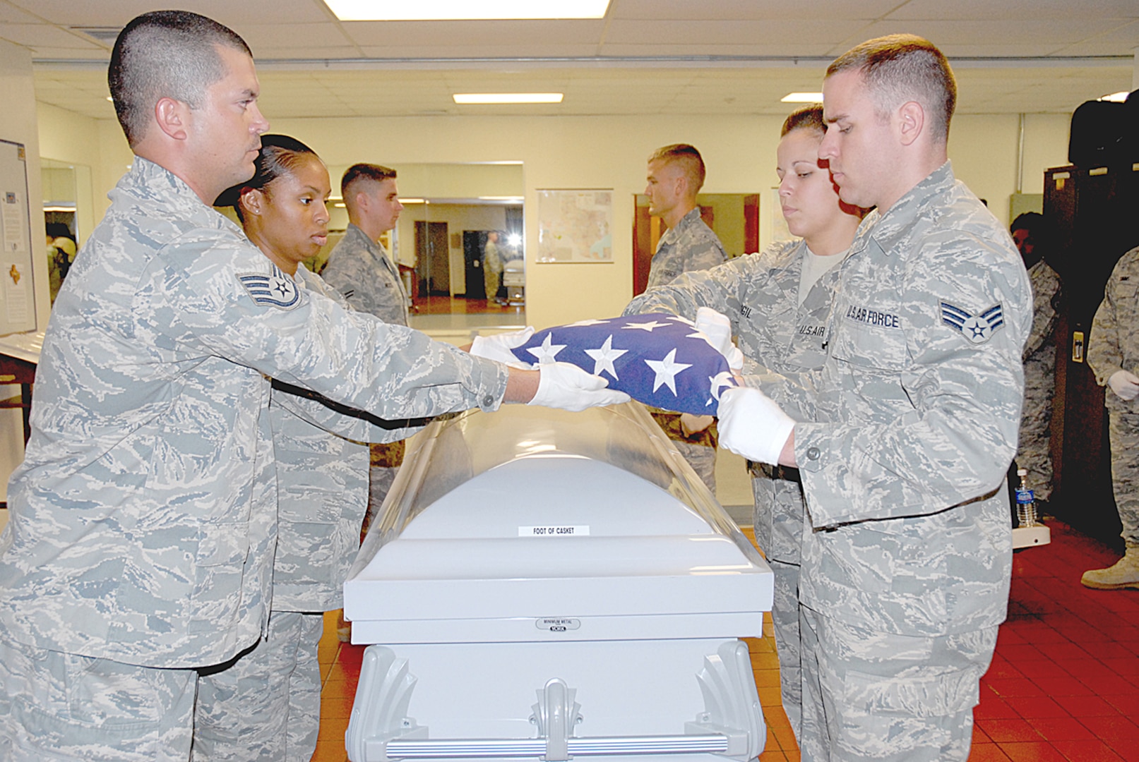 Members of the 12th Force Support Squadron ceremonial guard staff (from left to right), Staff Sgt. Michael Whitman, Staff Sgt. Ronetta Jones, Airman 1st Class Kyle Hicks, Senior Airman Bradley Blair, Senior Airman Patricia Vigil and Senior Airman James Lacey practice folding the American flag over a casket.