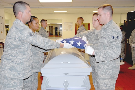 Members of the 12th Force Support Squadron ceremonial guard staff (from left to right), Staff Sgt. Michael Whitman, Staff Sgt. Ronetta Jones, Airman 1st Class Kyle Hicks, Senior Airman Bradley Blair, Senior Airman Patricia Vigil and Senior Airman James Lacey practice folding the American flag over a casket.