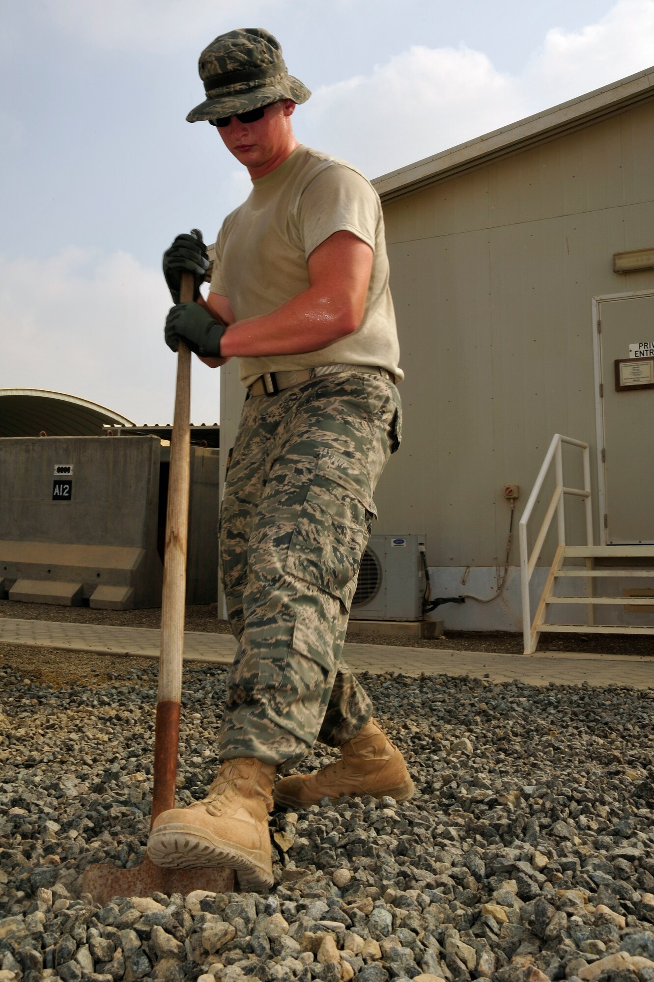 SOUTHWEST ASIA -Senior Airman Grant Coultas, 380th Expeditionary Civil Engineer Squadron, digs into gravel with a shovel to evenly spread the rocks while landscaping Sept. 03, 2009. Airman Coultas is deployed from Little Rock Air Force Base, Ark., and grew up in Bellevue, Neb. (U.S. Air Force photo/Tech. Sgt. Charles Larkin Sr)