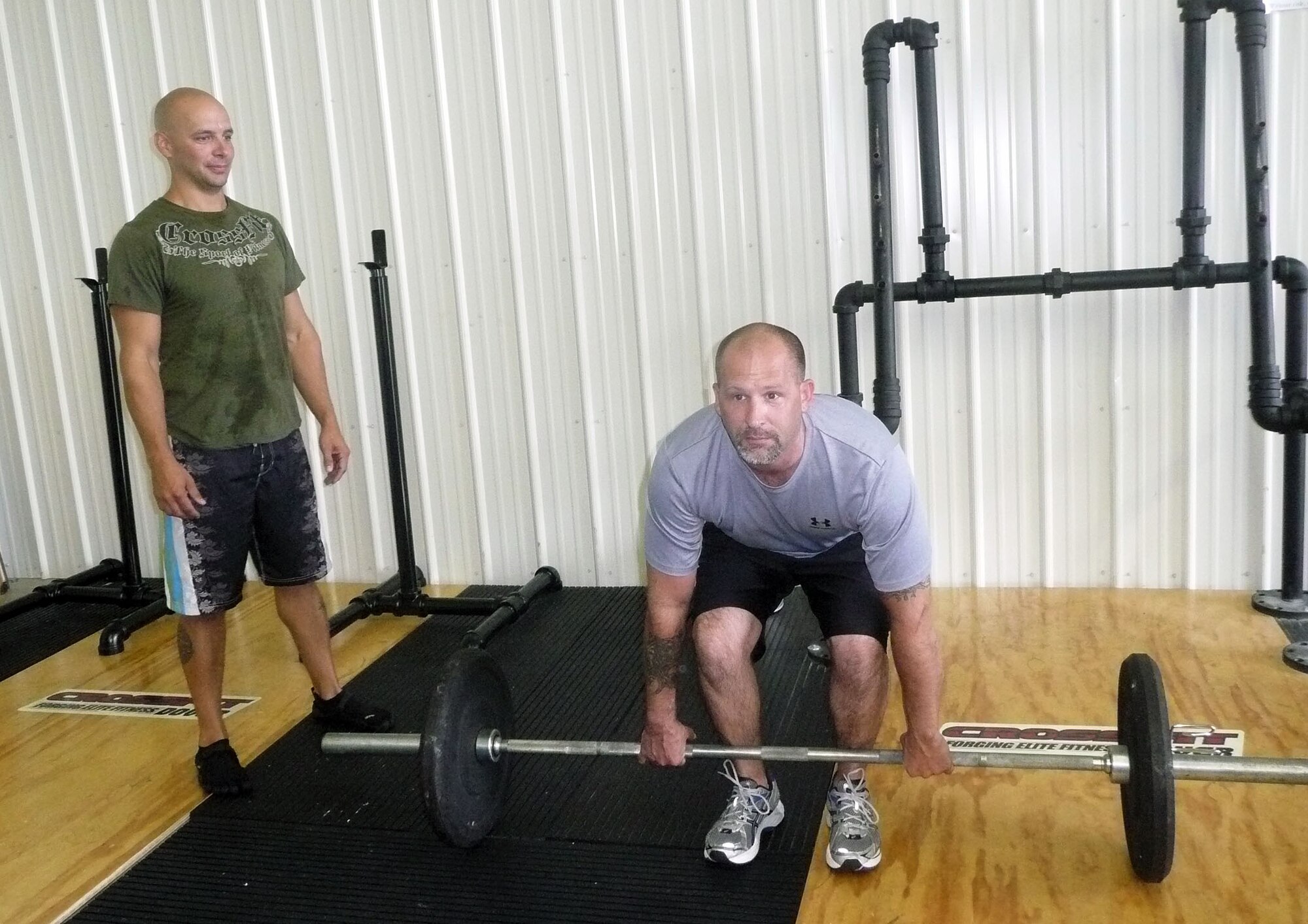 Master Sgt. Phillip Vickery, 326th Airlift Squadron loadmaster and CrossFit trainer, assists Master Sgt. Jeremy Lee, 709th Airlift Squadron, during a recent workout session. This summer, about 20 reservists from the 512th Airlift Wing started the CrossFit training program, which uses constant variation, high intensity and functional movements such as pushing, pulling, squatting, lifting or running. (U.S. Air Force photo/Capt. Shirley Whitney)

