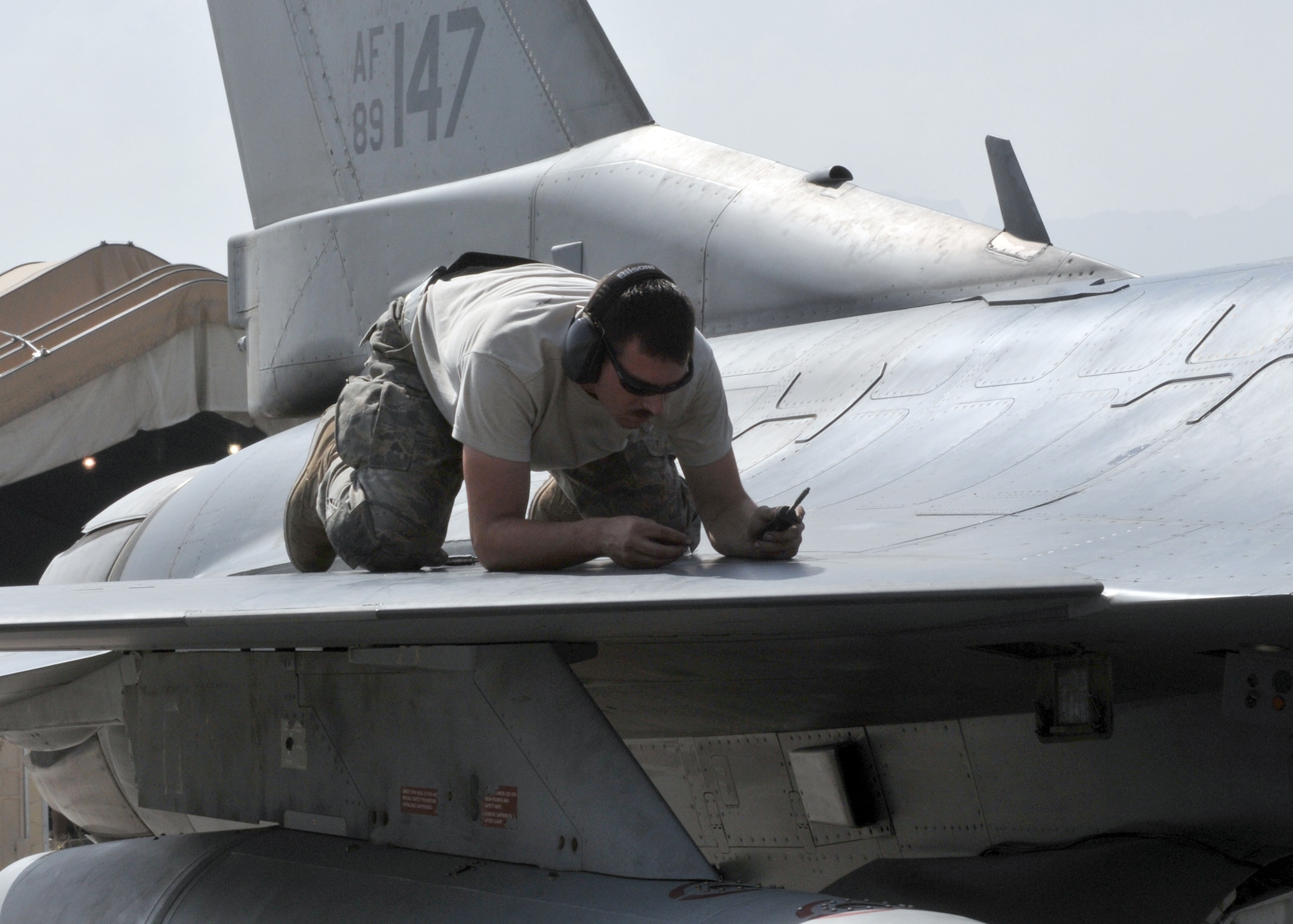 BAGRAM AIRFIELD, Afghanistan -- Airman 1st Class Jeremy Fath, deployed from Hill Air Force Base, Utah, inspects a panel on the wing of an F-16 here, Aug. 30, 2009.  The crew chiefs perform inspections to check and recheck the aircraft for cracks, broken pieces or anything out of the ordinary to ensure the safety of the pilots.  Airman Fath is a crew chief from the 455th Expeditionary Aircraft Maintenance Squadron and hails from Des Moines, Iowa.  (U.S. Air Force photo/Senior Airman Felicia Juenke)