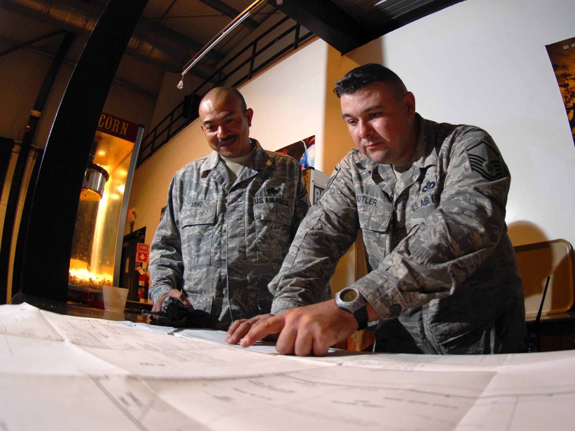 Left, Senior Master Sgt. Arnel Abad, 379th Expeditionary Civil Engineer Squadron zone superintendent and Master Sgt. Mark Butler, 379 ECES zone electrical NCOIC, review blueprints for the upcoming theater upgrade project, here, Sept. 3. Sergeant Abad is deployed from Seymour-Johnson Air Force Base, N.C. Sergeant Butler is deployed from Ellsworth Air Force Base, S.D. Both servicemembers are deployed in support of Operations Iraqi and Enduring Freedom.  (U.S. Air Force Photo/Tech. Sgt. Jason W. Edwards)
