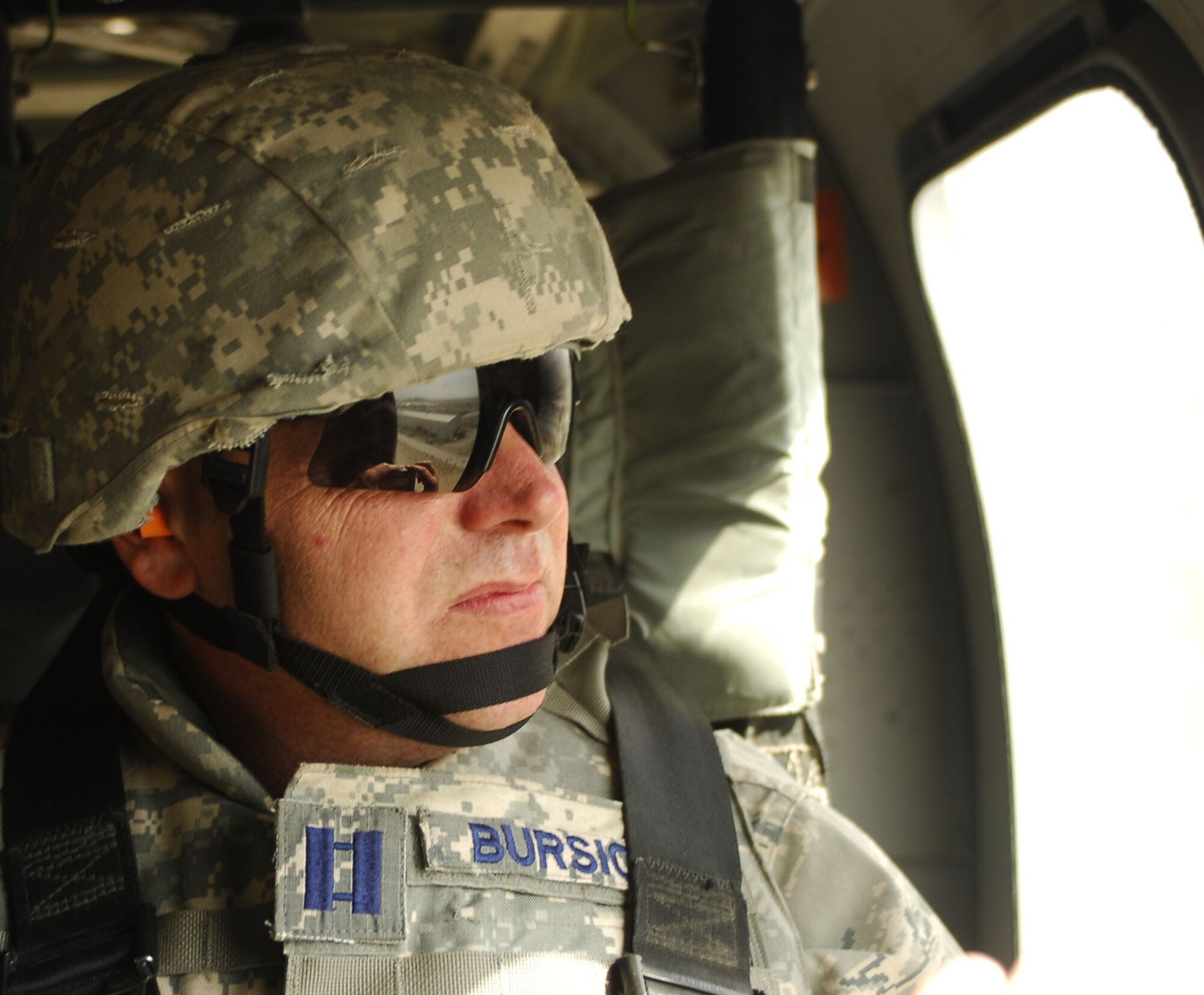 ABOVE AFGHANISTAN - Capt. Steve Bursick, 755th Air Expeditionary Group executive officer, gazes out at Forward Operating Base Lightning from a U.S. Army Blackhawk window, Aug. 30, 2009.  Airmen assigned to FOB Lightning are there as Joint Expeditionary Tasked Airmen who work day to day for U.S. Army Commanders while they're also assigned administratively to U.S. Air Force commanders under the 755th Air Expeditionary Group at Bagram Airfield, Afghanistan.  The JET Airmen are part of the Embedded Training Team here, which mentors Afghan National Army Forces.  The visit by Capt. Bursick and other Air Force leaders was designed to check up on Airman morale and readiness, while also thanking the Airmen for their work in the remote part of Afghanistan. (U.S. Air Force photo/Capt. David Faggard)