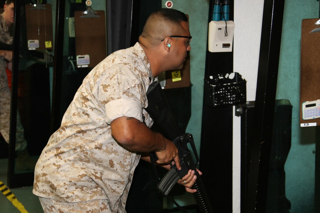 Gunnery Sgt. Rodney Buentello stands at the ready position waiting for his target to appear in the indoor small arms range here Friday. Buentello took second place in the shooting competition finishing four points behind Cpl. Justin Hudnall, a Provost Marshall’s Office military police officer.
