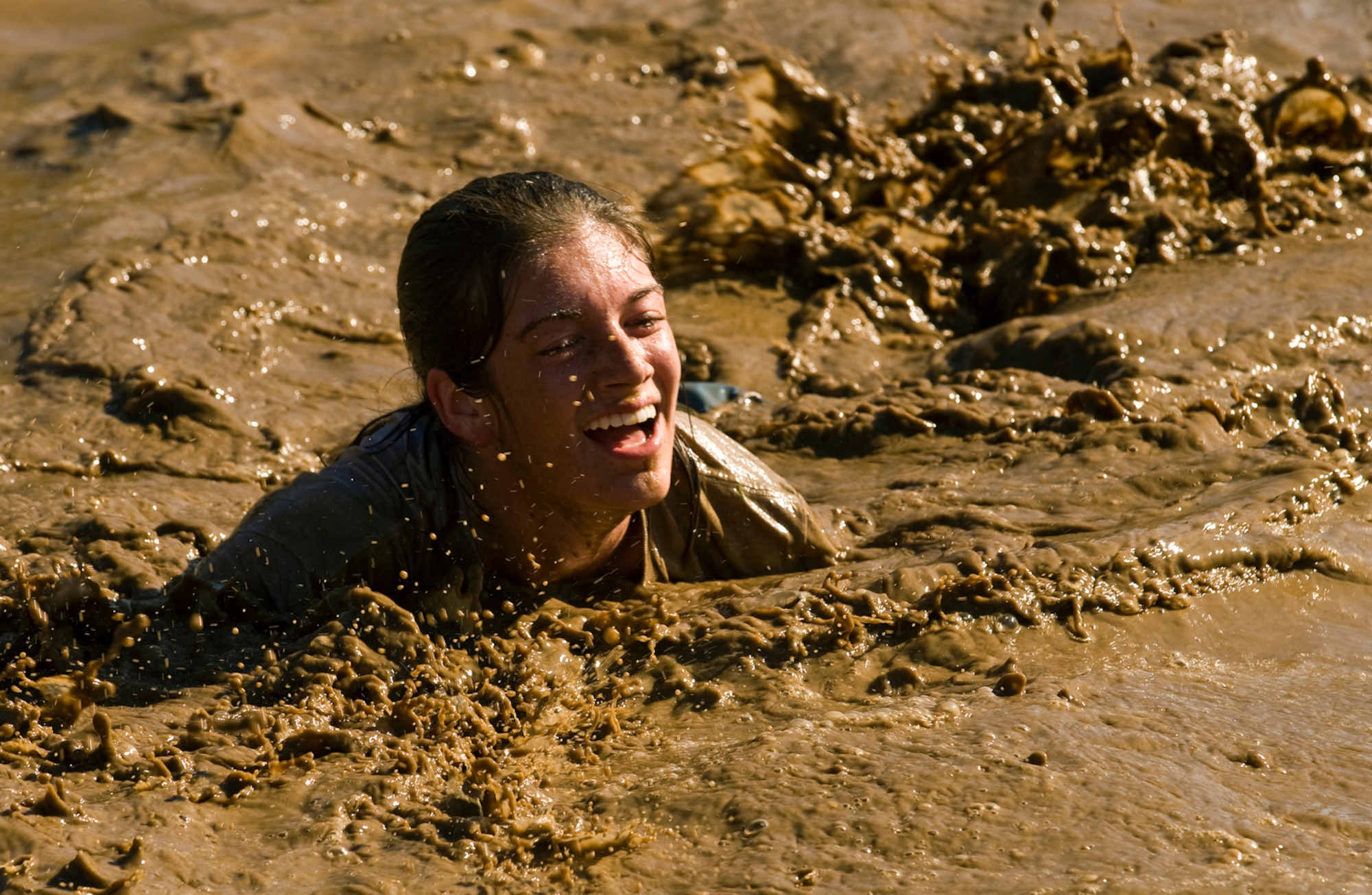 Staff Sgt. Lindella Huguet laughs her way through the mud during the 10th Annual Mather Mud Run in Rancho Cordova, Calif., Sept. 5, 2009, for Air Force Week Sacramento. The Mud Run features a 5-mile or 2-mile obstacle course boot camp challenge featuring low walls, tunnel crawls, tire run, hay bale jumps and a low-crawl mud pit. Air Force Week Sacramento is an event using various activities and exhibitions to educate the local community about the Air Force's capabilities and missions. Sergeant Huguet is a member of the 615 Contingency Response Wing at Travis Air Force Base, Calif. (U.S. Air Force photo/Staff Sgt. Bennie J. Davis III) 