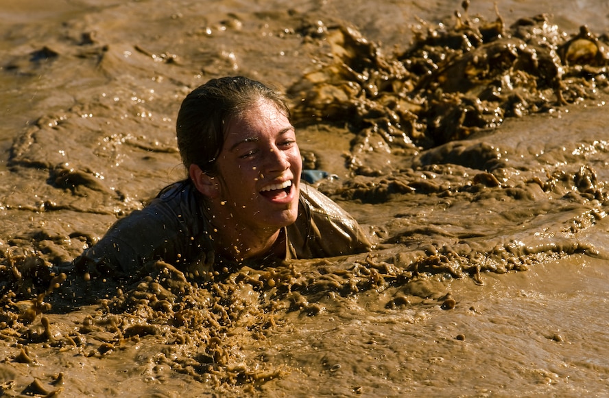 Staff Sgt. Lindella Huguet laughs her way through the mud during the 10th Annual Mather Mud Run in Rancho Cordova, Calif., Sept. 5, 2009, for Air Force Week Sacramento. The Mud Run features a 5-mile or 2-mile obstacle course boot camp challenge featuring low walls, tunnel crawls, tire run, hay bale jumps and a low-crawl mud pit. Air Force Week Sacramento is an event using various activities and exhibitions to educate the local community about the Air Force's capabilities and missions. Sergeant Huguet is a member of the 615 Contingency Response Wing at Travis Air Force Base, Calif. (U.S. Air Force photo/Staff Sgt. Bennie J. Davis III) 