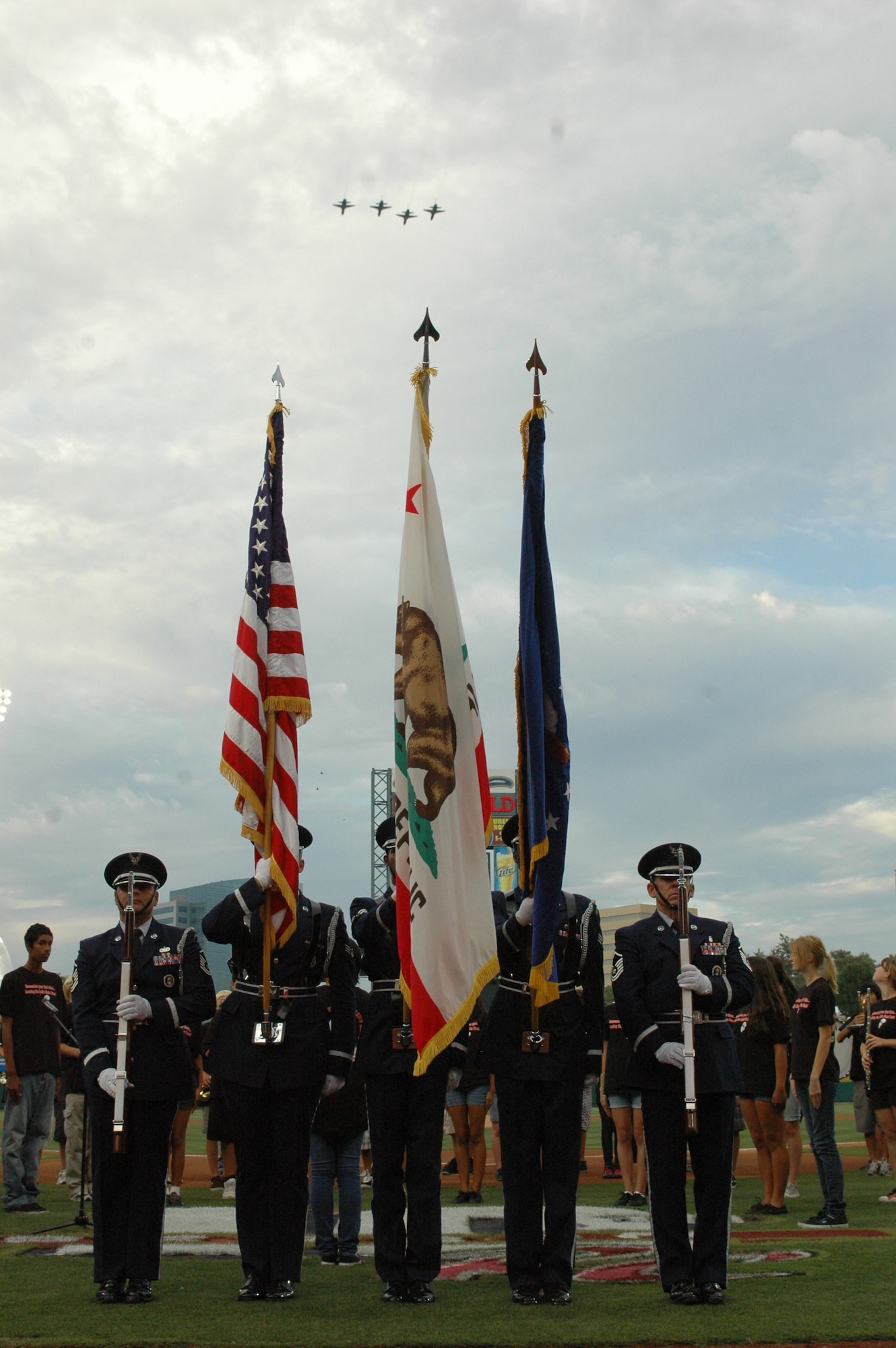 Travis AIr Force Base Honor Guard members present the colors as a formation of four T-38 Talon aircraft form Beale Air Force Base, Calif., fly overhead at the end of the playing of the National Anthem at the start of the Sacramento Rivercats game Aug. 28 at Raley Field. (U.S. Air Force photo/2nd Lt. Holly Hess)